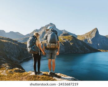 Couple backpackers hiking in mountains friends exploring Norway together active healthy lifestyle outdoor family summer vacations adventure trip, man and woman enjoying lake view in Lofoten islands - Powered by Shutterstock