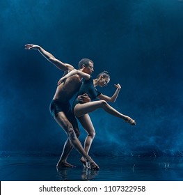 The couple of ballet dancers dancing under water drops and spray. Young caucasian and afro american models. Man and woman dancing together. Ballet and contemporary choreography concept. Art photo - Powered by Shutterstock