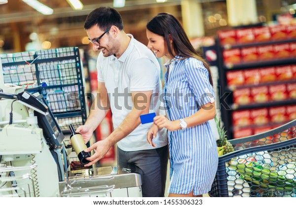 Couple with bank card buying food at\
grocery store or supermarket\
self-checkout