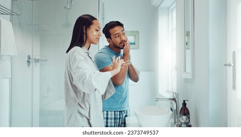 Couple, bathroom and cleaning face with cream, skincare and comic joke with laughing, serum or product. Man, woman and funny with facial oil moisturizer for beauty, wellness or self care in apartment - Powered by Shutterstock