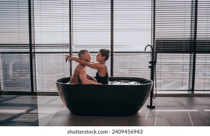 Couple in bathtub, intimate moment with cityscape background, modern luxury. - Powered by Shutterstock