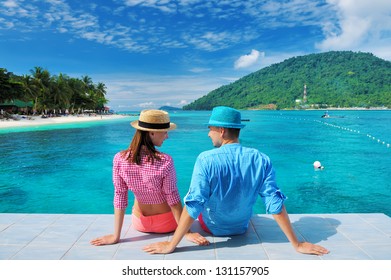Couple at beach jetty wearing hat