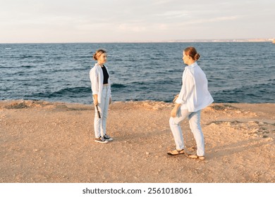 Couple Beach Sunset - Two people in white clothing stand on a sandy beach facing the ocean at sunset. - Powered by Shutterstock