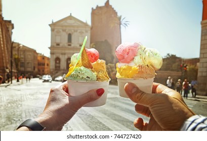 Couple with beautiful bright  sweet Italian ice-cream with different flavors  in the hands   on the square in Rome , Italy