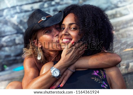 couple of beautiful women of different ethnicity while hugging on beach vacation