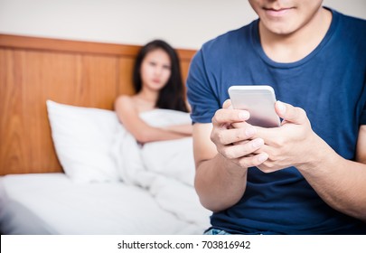 Couple in bed, happy smiling man turned her back to man, reading message on phone from her lover, worried woman lying next to her, trying to peek at screen. Cheating and infidelity concept