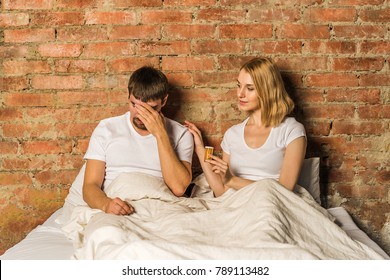 Couple In Bed.  Sad Man And Woman With Medicine Pills In Hand. Sexuality And Impotence Problem Concept.