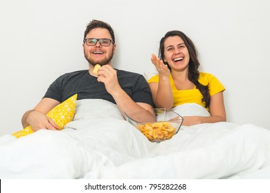 Couple In The Bed Watching TV With Beer And Snacks