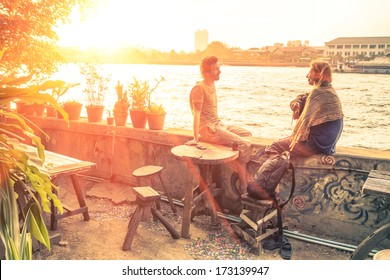 Couple of best friends travelers talking at sunset - Travel concept around the world with exclusive destinations - Young hipster wanderers relaxing and enjoying alternative holidays life experiences - Powered by Shutterstock