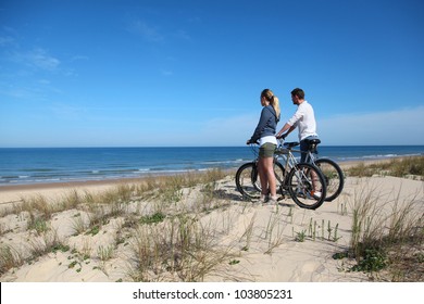 Couple with bicycles looking at the ocean