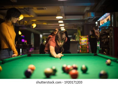 Couple in billiard room. Man playing billiard. Focus is on man. 