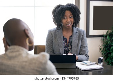 Couple of black female businesswomen or partners arguing at work or a bossy manager doing a job interview or perfomance review to an employee and looking disappointed. 