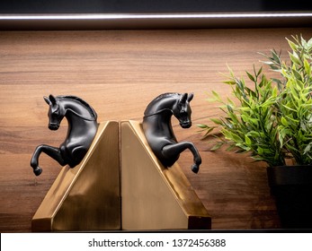 Couple Of Black Horses Book Ends Made From Metal With Green Plant On Pot Displayed On Wooden Shelf With LED Strip Lighting And Wood Background.no Book Props Setting, Decorative Items For Interior.