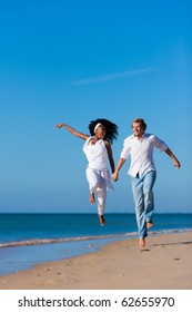 Couple - Black Woman And Caucasian Man Ã¢Â?Â? Having A Walk Jumping On A Beach In Their Vacation