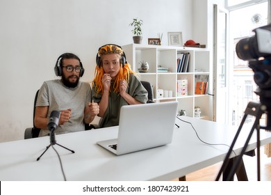 Couple Of Bloggers, Young Man And Woman Looking Scared While Watching Something On Laptop, Recording Reaction Video Blog Or Vlog. Content Creator, Filming, Blogging. Horizontal Shot