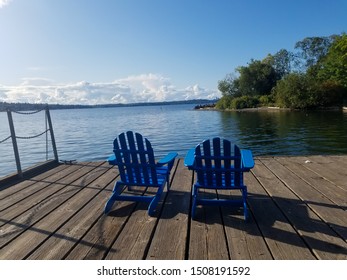 A Couple Of Blue Chairs On The Old Wooden Pier For Relaxation With The Lake Washington Views. Retirement Concept.