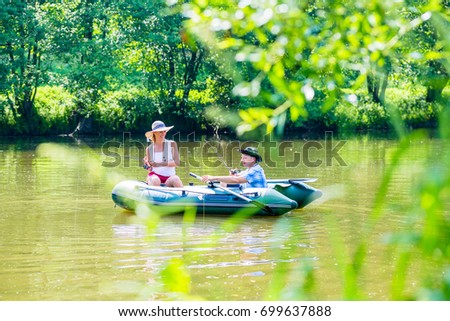 Couple in boat on pond or lake fishing, woman with angle and man is steering