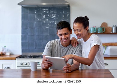 couple bonding and enjoying morning coffee with tablet computer in kitchen at home