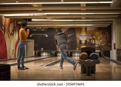 Couple In Bowling Alley. Man Throwing A Bowling Ball.