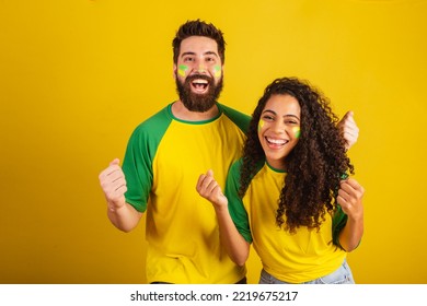 couple of brazil soccer supporters, dressed in the colors of the nation, black woman, caucasian man. Twisting and vibrating. - Shutterstock ID 2219675217