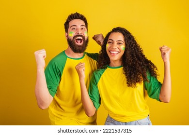couple of brazil soccer supporters, dressed in the colors of the nation, black woman, caucasian man. Twisting and vibrating.