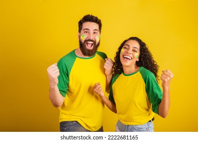 couple of brazil soccer supporters, dressed in the colors of the nation, black woman, caucasian man. Twisting and vibrating. - Powered by Shutterstock