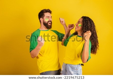couple of brazil soccer supporters, dressed in the colors of the nation, black woman, caucasian man. Twisting and vibrating.