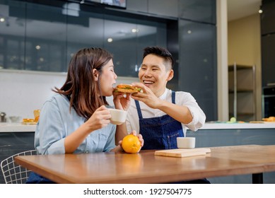 A Couple With A Breakfast Sandwich Inside The Kitchen Background
