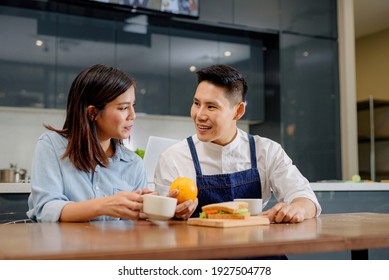 A Couple With A Breakfast Sandwich Inside The Kitchen Background
