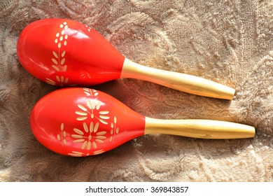 Couple Of Bright Red Wooden Maracas On Brown Background In Sunny Day