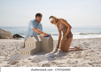 Couple Building Sandcastle Shaped Like House