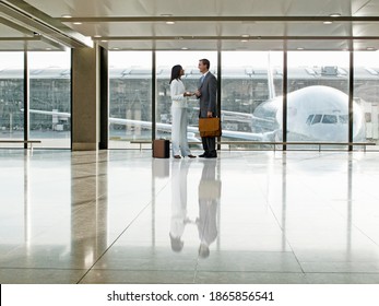 Couple Of Business People Standing And Talking Together In An Airport Terminal