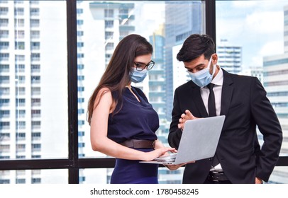 Couple of business people workers meeting in modern office together with laptop, Business people working with face mask quarantine from coronavirus or COVID-19 - Powered by Shutterstock