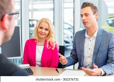 Couple buying car at dealership and negotiating price with salesman