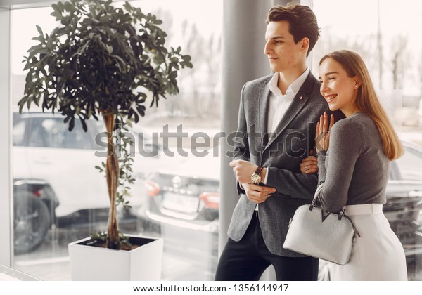 Couple buying the car. Pair in a car salon.\
Husband with vife choose the\
automobile