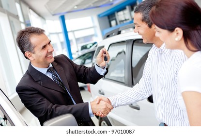 Couple Buying A Car And Salesman Handling Keys