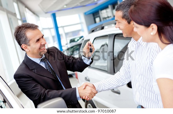 Couple buying a\
car and salesman handling\
keys