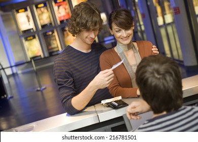 A Couple Buying Movie Tickets At The Box Office.