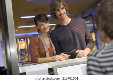 A Couple Buying Movie Tickets At The Box Office.