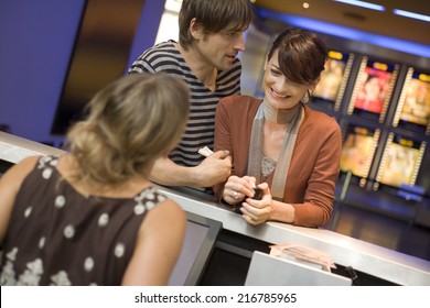 A Couple Buying Movie Tickets At The Box Office.