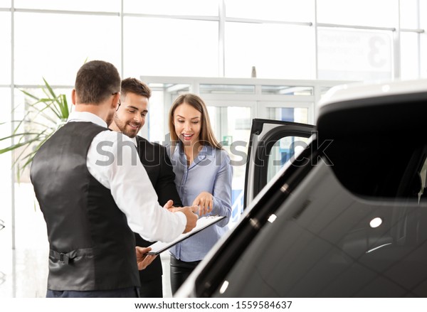 Couple buying new car in\
salon