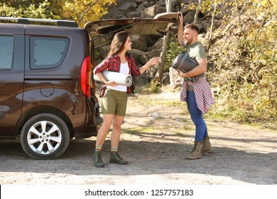 Couple Of Campers With Sleeping Bag And Mat Near Car Outdoors