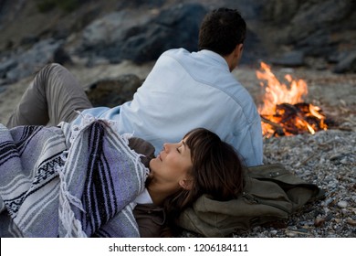 Couple Camping On The Beach By The Fire