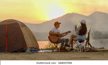 Couple at campsite after make tent playing guitar and sing together - Powered by Shutterstock