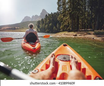 Couple canoeing in the lake on a summer day. Man and woman in two different kayaks in the lake on a sunny day.