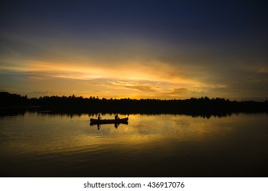 Couple Canoeing On A Calm Lake During Sunset