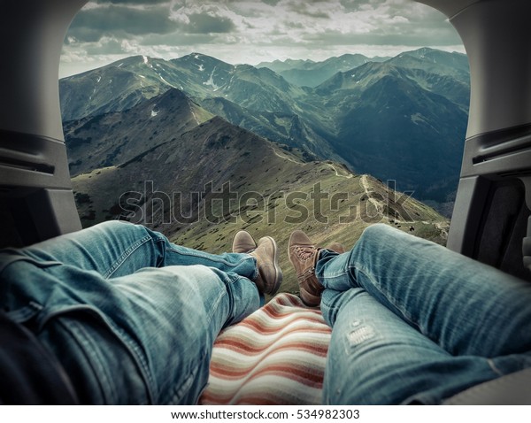 Couple in car.\
Blonde female and male in jeans in them car looking on beautiful\
mountains view at autumn\
day.