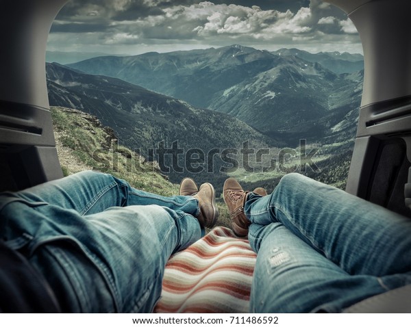 Couple in car.\
Blonde female and male in jeans in them car looking on beautiful\
mountains view at autumn\
day.