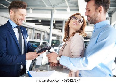 Couple At Car Dealer Buying New Car 