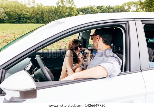 couple in a car having fung on plying with a old\
fashioned photo camera. love, summer, holiday, travel, relax, joy,\
togetherness concept